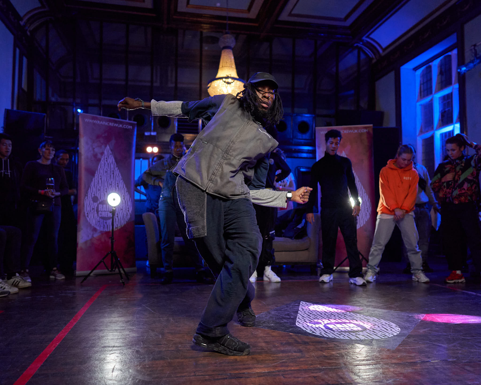 A guy dancing on stage followed by a rival dancer watching close by