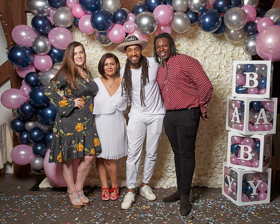 four people standing next to each other posing for a photograph smiling