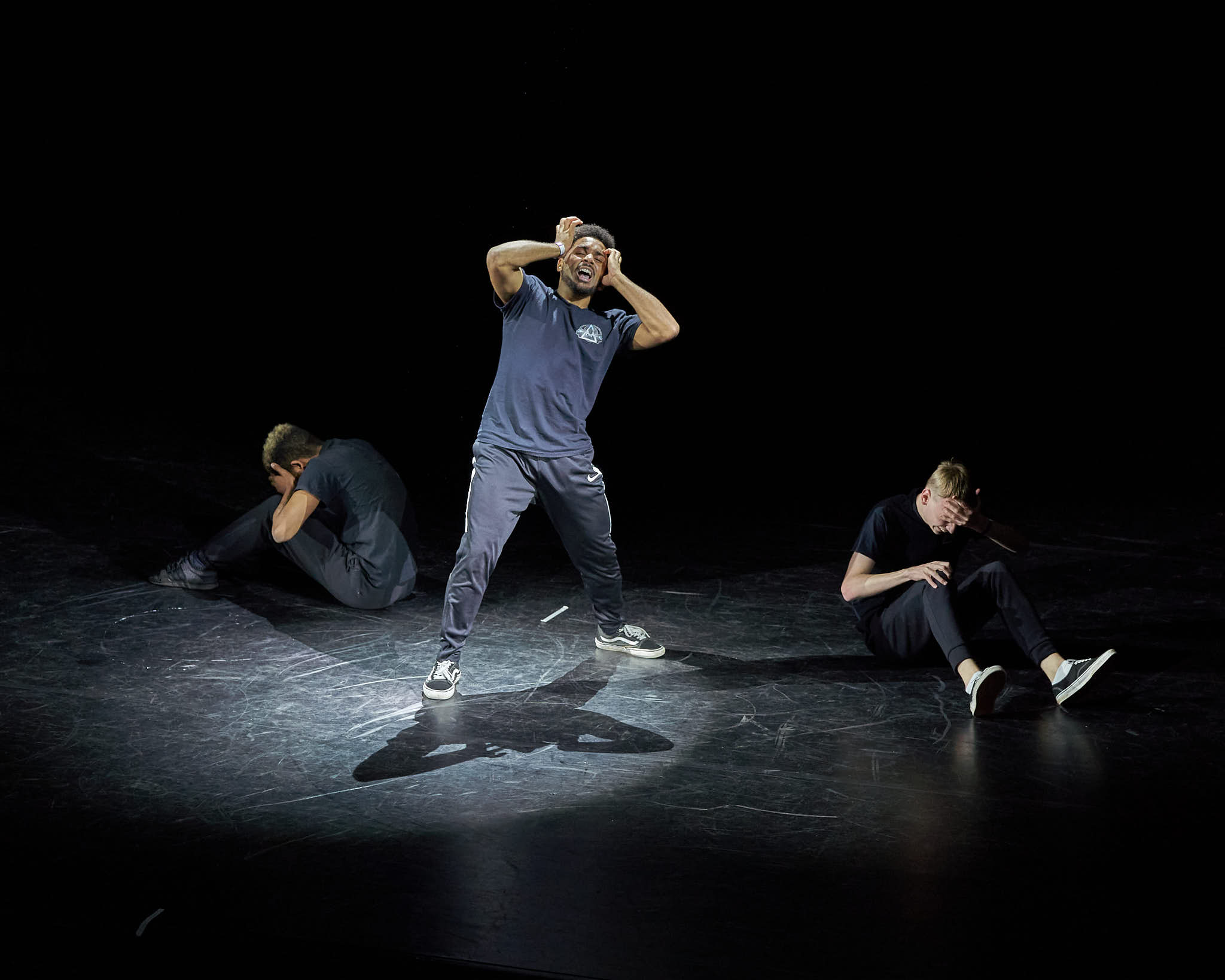 A group of people acting out a theatrical play, with the man in the middle showing despair and the others on the side, emotion of sorrow.