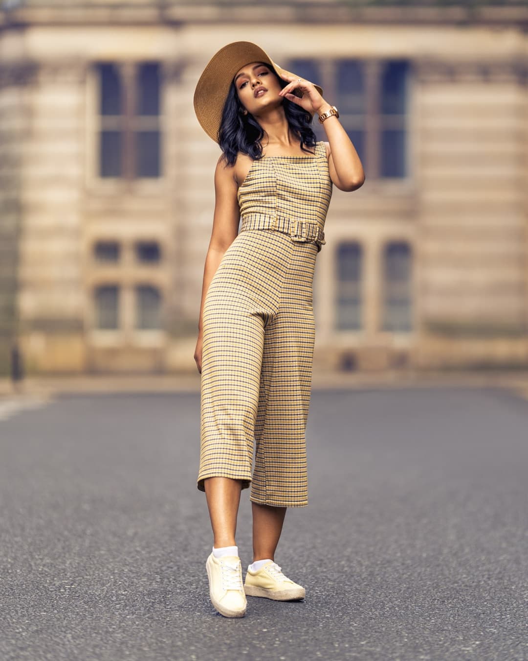 A woman posing infront of a building in beige clothing