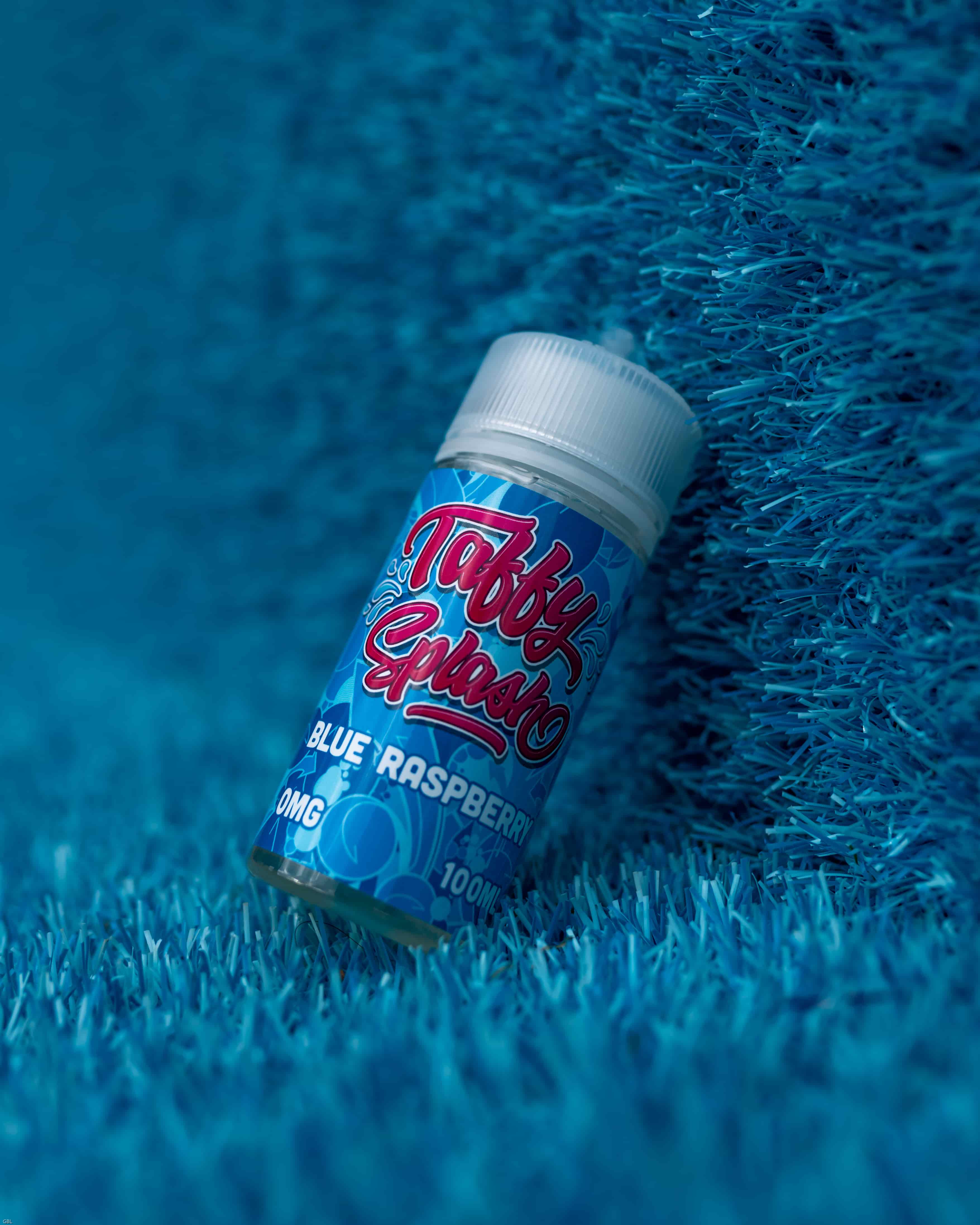 A liquid for E-cigarette in blue, leaning on a wall of plastic grass, also in blue